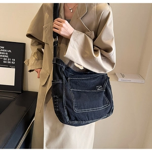 Dettaglio della borsa a tracolla in denim nero con cuciture a contrasto e bordi sfrangiati