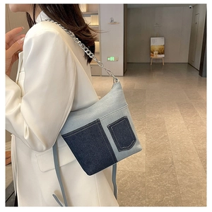 Detail shot of the two-tone denim bucket bag with thick silver chain strap and metal texture