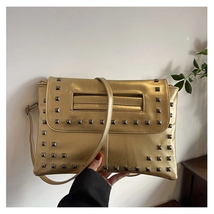 Dettaglio della borsa a busta dorata metallizzata con borchie nere e tracolla sottile chic