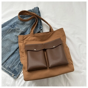Close-up of brown canvas tote bag with retro faux leather pockets and metal buckles