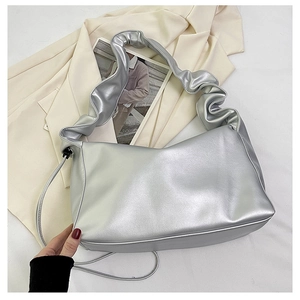 Detailed view of silver baguette bag with ruched shoulder strap and metallic finish