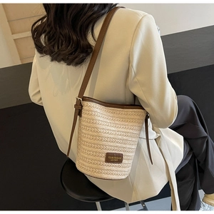 Detailed view of hand-woven straw bucket bag texture with premium brown leather strap