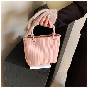 Detailed texture of pink pleated bucket bag with round handle and soft gloves