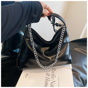 Detailed shot of black glossy leather hobo bag with thick silver metal chain and shoulder strap