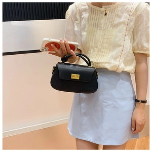 Close-up of the black leather textured handbag with a gold metal clasp and top handle