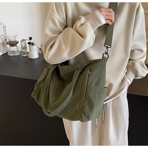 Detail of army green corduroy tote bag showing textured fabric and wide strap in use