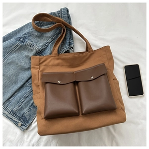 Detail shot of canvas tote bag featuring brown utility pockets with silver snap buttons