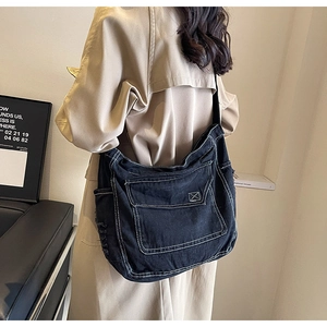 Dettaglio della borsa a tracolla in denim nero con cuciture bianche e ampie tasche