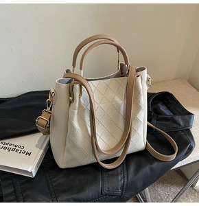Close-up of cream white bucket bag with diamond lattice pattern and brown handles