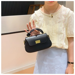 Detail of a black matte leather handbag with gold metal twist lock and knotted handle