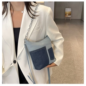Detail view of denim patchwork crossbody bag with silver chain strap on model