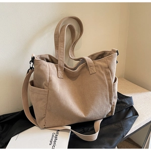 Detailed close-up of corduroy tote bag texture with side pocket and fabric strap