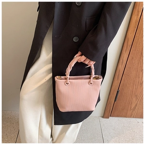 Detail of light pink pleated bucket bag with a unique woven rope handle and gold hardware