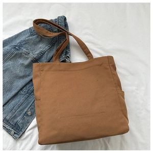 Flat lay of brown canvas tote bag with side pockets and stylish rectangular stitching detail