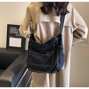 Dettaglio della borsa a tracolla in denim nero con cuciture bianche e bordi grezzi