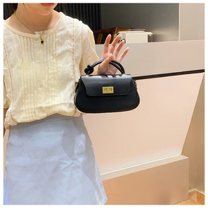 Detail of black matte leather handbag with a gold twist lock and elegant knot handle