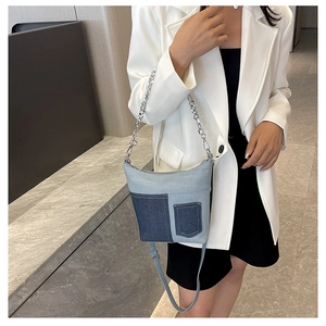 Detail view of patchwork denim bucket bag with mini pocket and silver chain on model