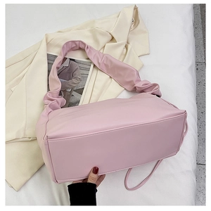 Detail view of pink ruched shoulder bag showing soft faux leather texture and folded strap