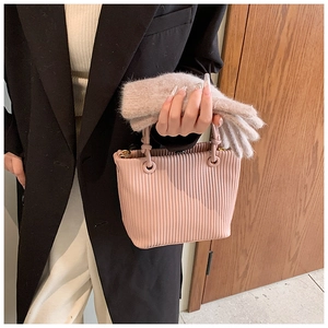 Detail of pink pleated bucket bag paired with soft beige plush faux fur gloves