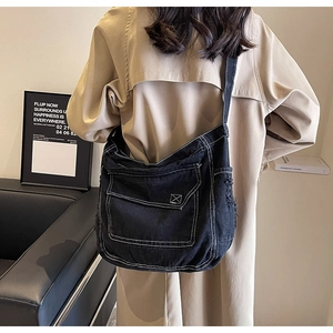 Vista dettagliata della borsa a tracolla in denim nero con cuciture bianche e bordi sfrangiati
