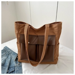 Detail of khaki canvas tote bag featuring brown leather front pockets and silver snap buttons