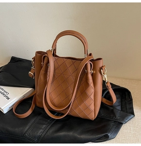 Close-up of caramel quilted leather bucket bag with golden hardware and round handles