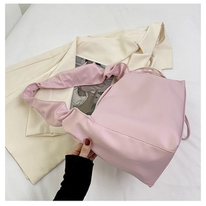 Detail of light pink baguette bag with large pleated cloud-shaped handle on white fabric