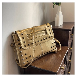 Dettaglio della borsa a busta in pelle dorata con decorazioni di borchie metalliche