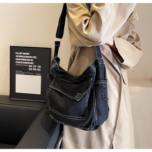 Dettaglio delle cuciture bianche e della tasca con patta sulla borsa a tracolla denim