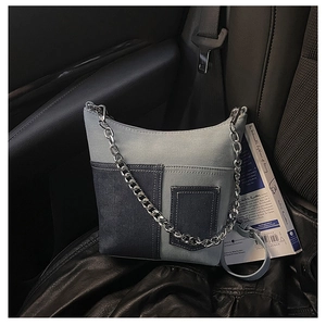 Detail of a color-block denim bucket bag with silver chains on a black car seat
