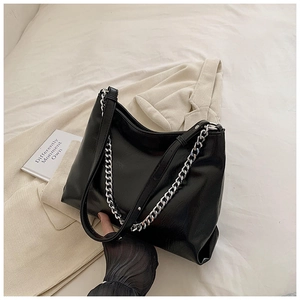 Close-up of black hobo bag with silver chain strap on beige corduroy background