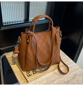 Detail of brown litchi leather bucket bag featuring gold metal handles and diamond quilting