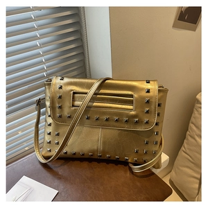 Dettaglio borsa a busta in pelle dorata con file di borchie quadrate in metallo