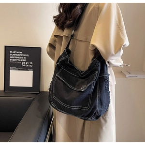 Dettaglio della borsa a tracolla in denim nero con cuciture bianche e cinturino regolabile