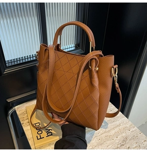 Close-up of caramel leather bucket bag with quilted patterns and golden hardware