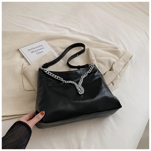 Close-up of black wrinkled texture leather bag with elegant V-shaped silver metal chain