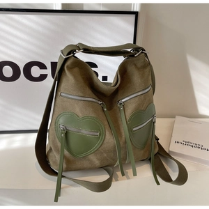 Detail view of corduroy backpack featuring green heart-shaped pockets and silver zippers