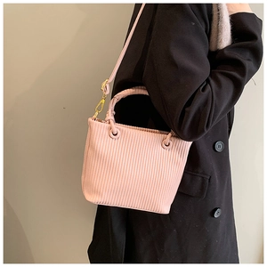 Detailed view of light pink pleated bucket bag with vertical stripes and woven handle