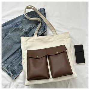 Detailed top view of off-white canvas tote bag with brown leather pockets and denim jacket