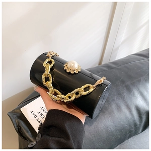 Detail view of cylindrical evening bag with gold chain and large pearl accent