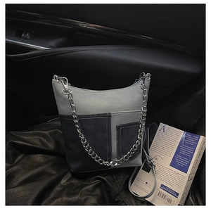 Detail of canvas shoulder bag with dual front pockets and silver chain strap