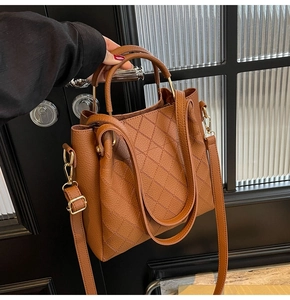 Detailed view of brown quilted leather bucket bag with gold hardware and top handle