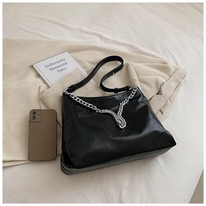 Detail of black pleated faux leather bag with chunky silver chain and slim strap