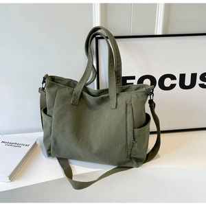 Close-up of green corduroy tote bag texture with functional side pocket and shoulder strap