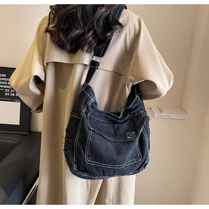 Dettaglio della borsa a tracolla in denim nero con cuciture a contrasto bianche e tracolla