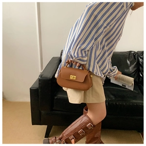 Minimalist brown leather half-moon bag featuring a gold twist lock and crossbody chain