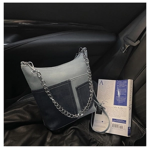Detailed shot of patchwork denim shoulder bag with silver chain on car leather seat