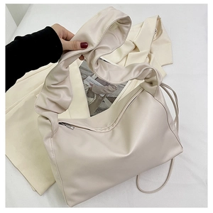 Detail shot of the cream-white baguette bag showing cloud-like pleated handles and zipper