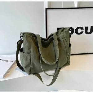 Detail of dark green corduroy tote bag with textured surface and adjustable shoulder strap