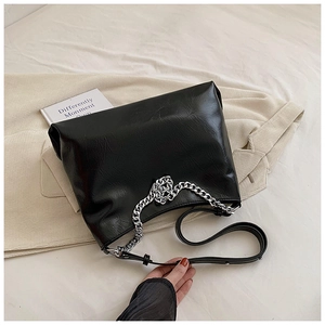 Detail of black pebbled leather tote bag with silver chain strap and matte texture finish